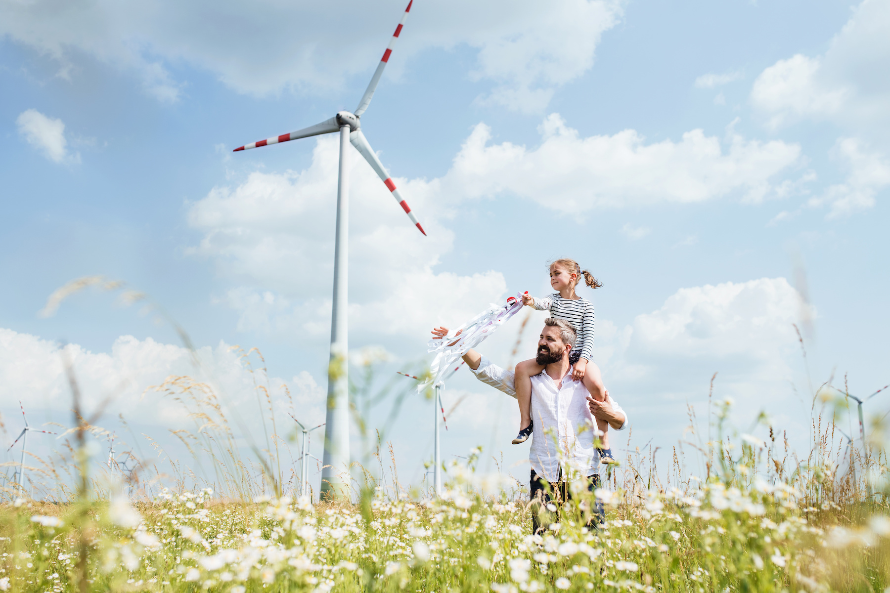 Father and daughter in field with wind farm
