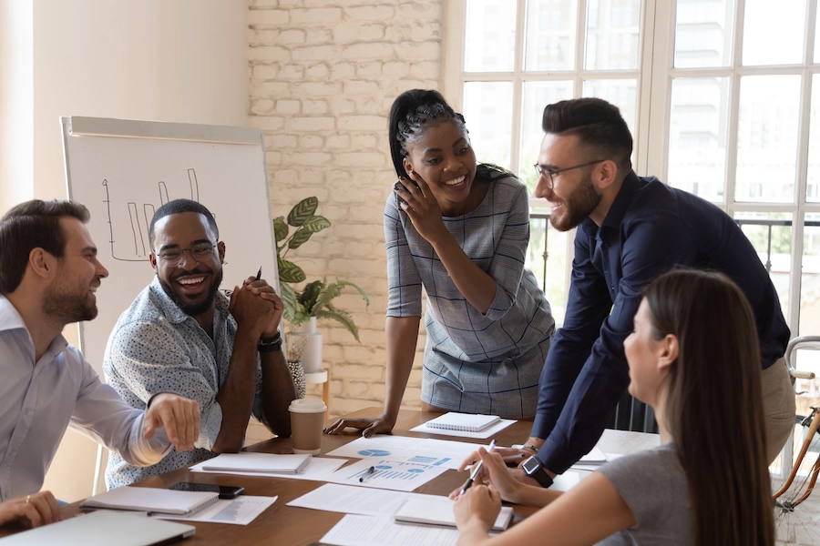 An image of colleagues discussing files laid out over a conference table