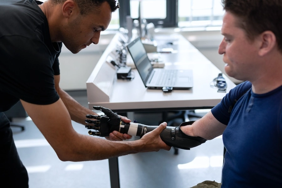 One person fitting another with a robotic arm. This image accompanies GrantTree's blog about business grants for UK startups