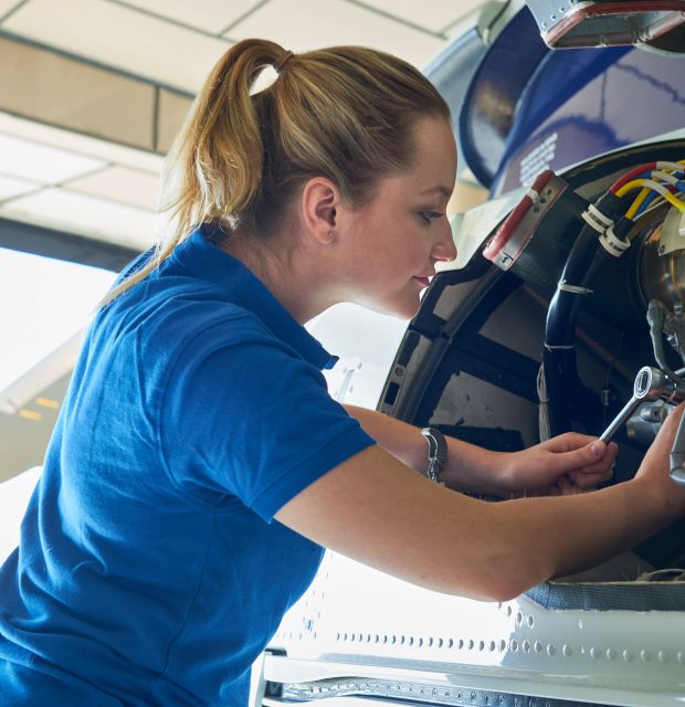 Female Aero Engineer Working On Helicopter In Hangar