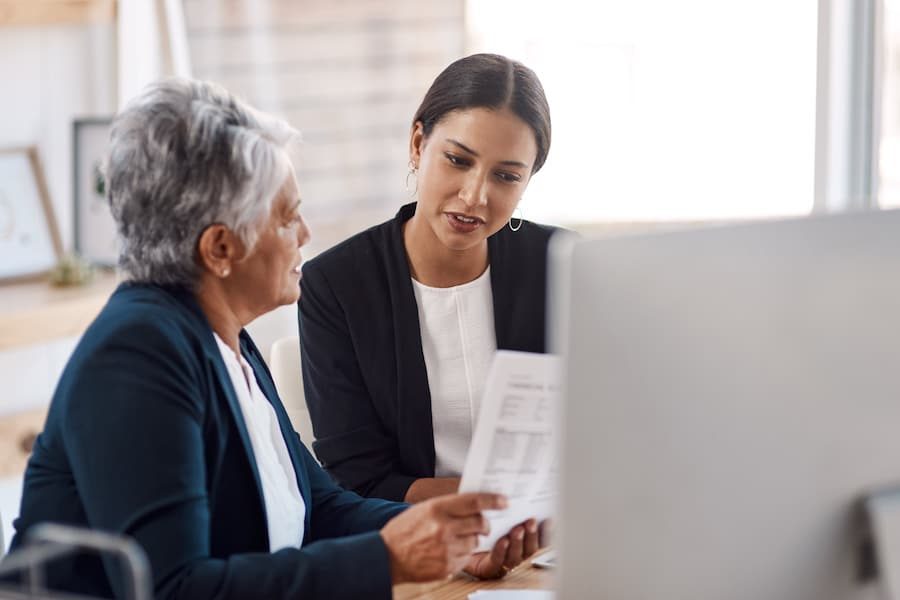 Mentor, coaching or business women with documents talking, speaking or planning project in office. Paperwork, teamwork collaboration or senior manager reading with intern for administration training.